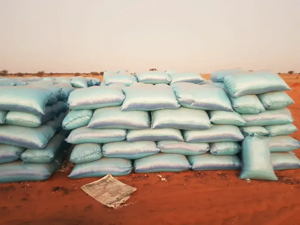 Sacks of harvested crop stacked on red soil, ready for collection